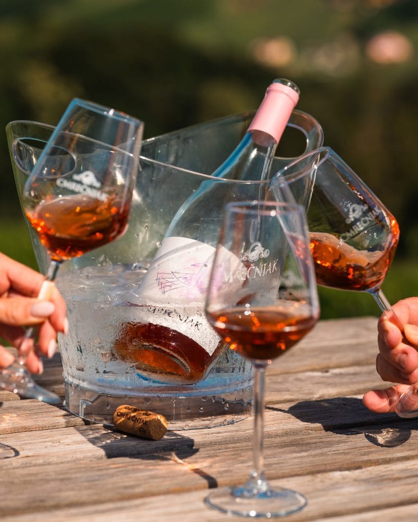 Vino u hladnjaku za vino s čašama na drvenom stolu.