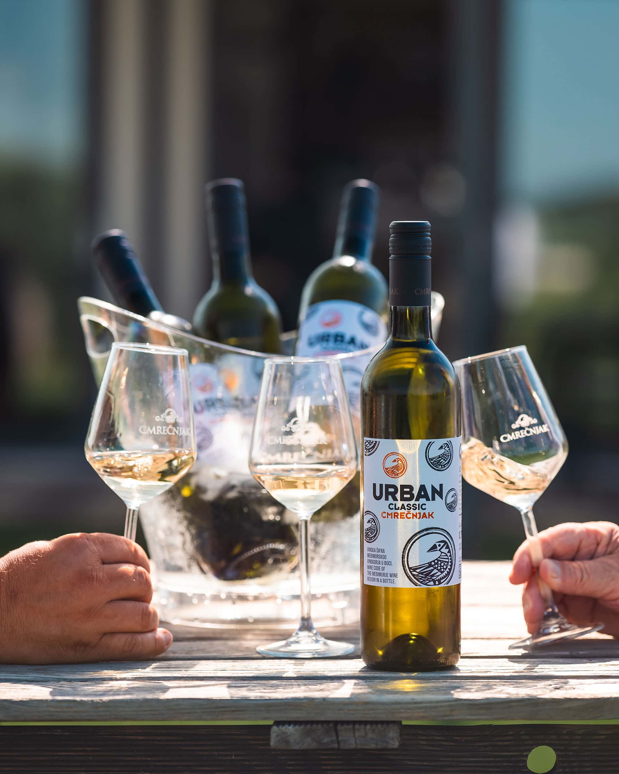 Vino u vinskoj čaši s bocama na terasi s pogledom na prirodu.
